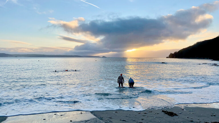 A picture of two swimmers in the sea at sunrise